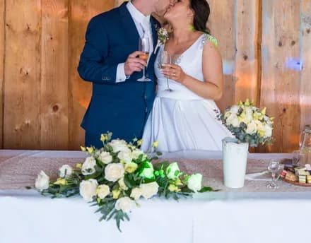 The couple sharing a kiss over champagne at their sweetheart table